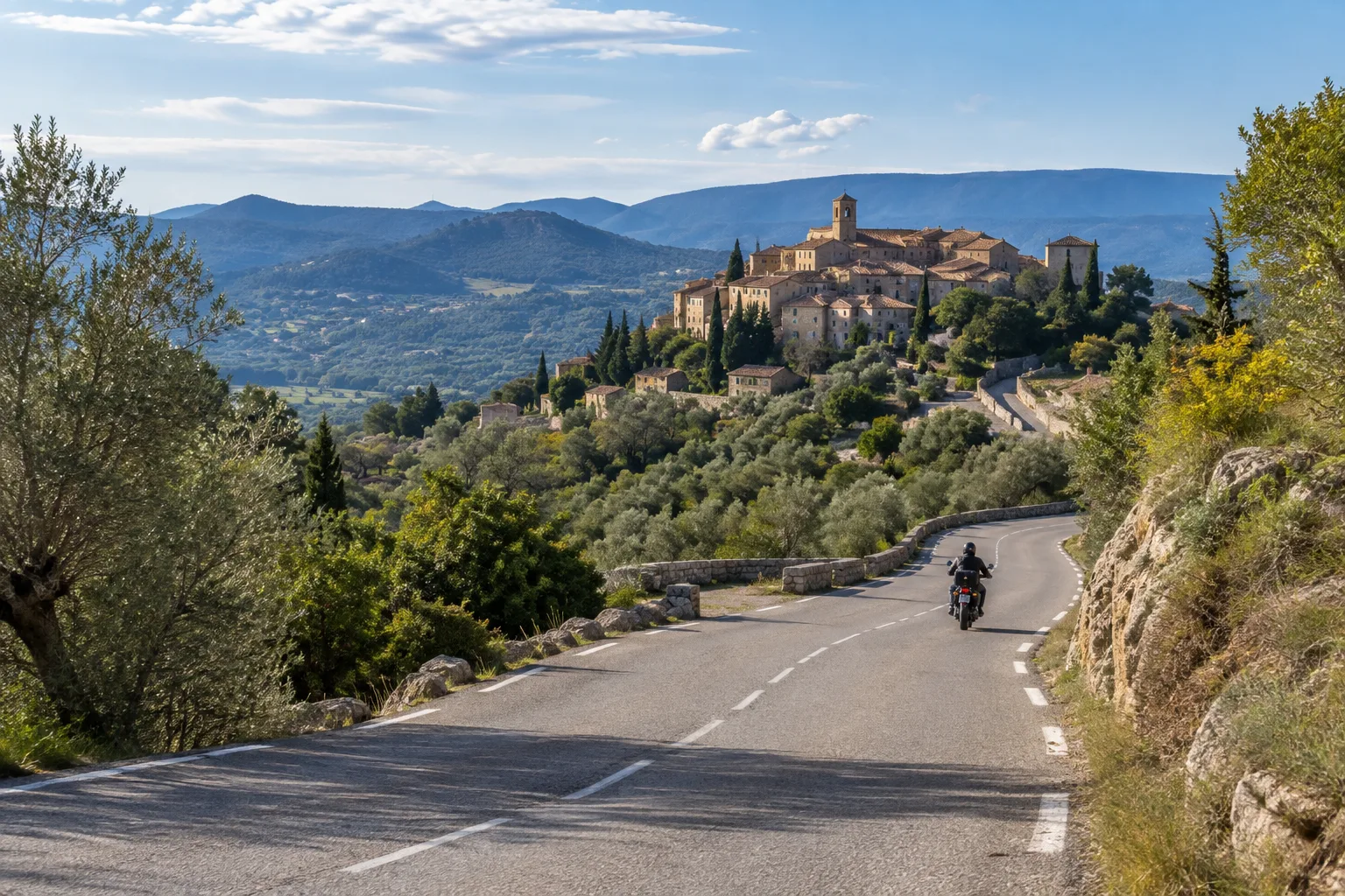 Une moto s’engage sur une route qui monte dans les collines de l’arrière-pays varois.