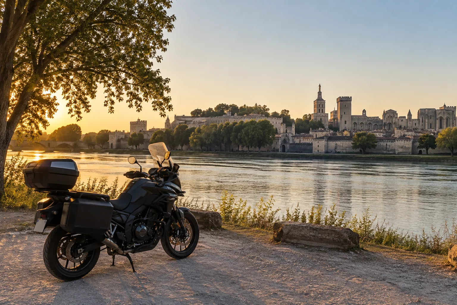 Les remparts d’Avignon vus depuis la Barthelasse, avec le Rhône au premier plan et une moto stationnée sur la rive.