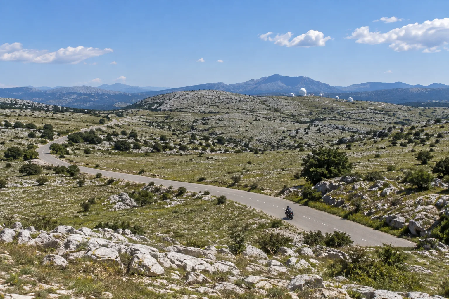Une petite route traverse les étendues calcaires et la végétation basse du plateau de Caussols.