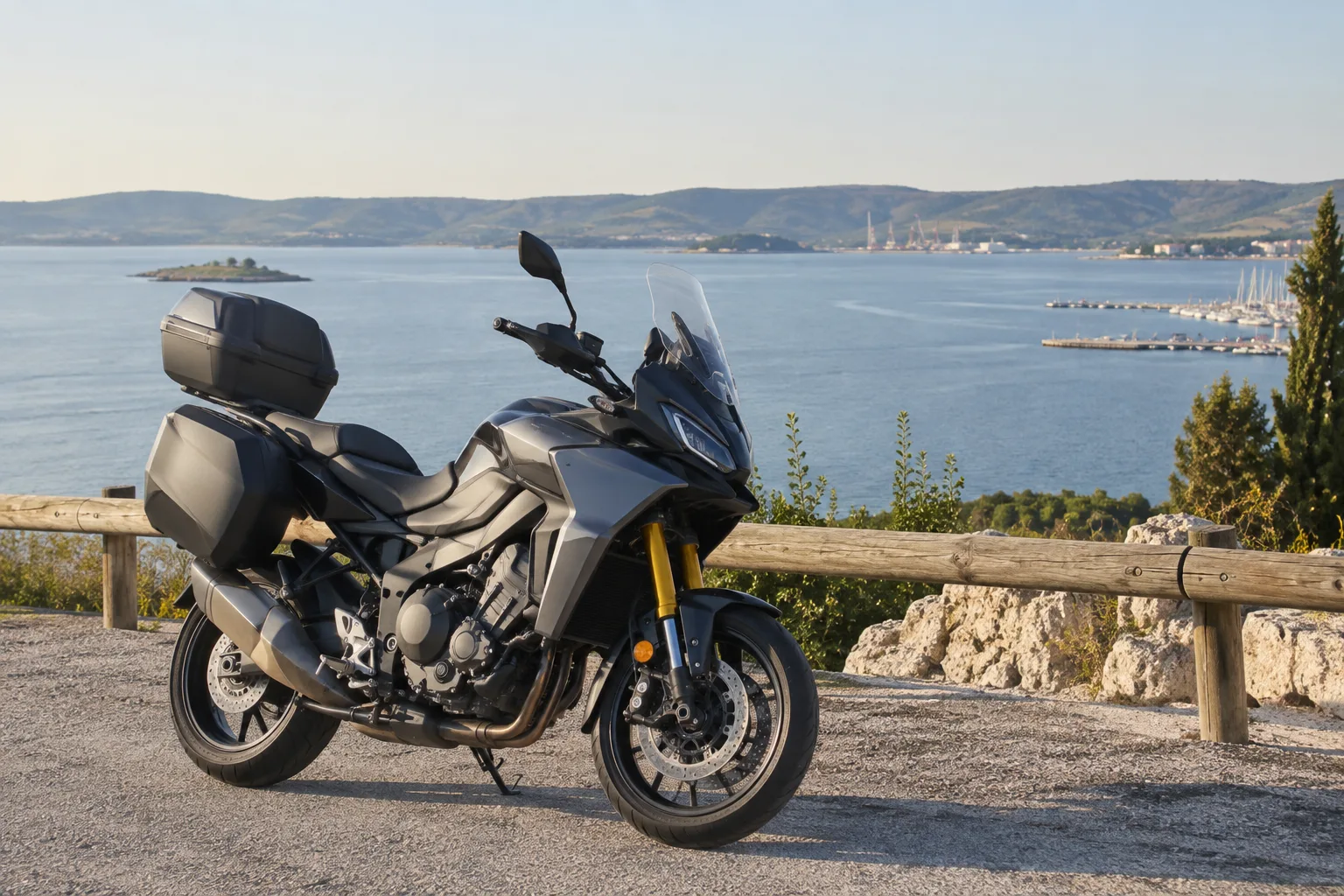 Une moto stationnée près d’une rive de l’étang de Berre, avec un port visible au loin.