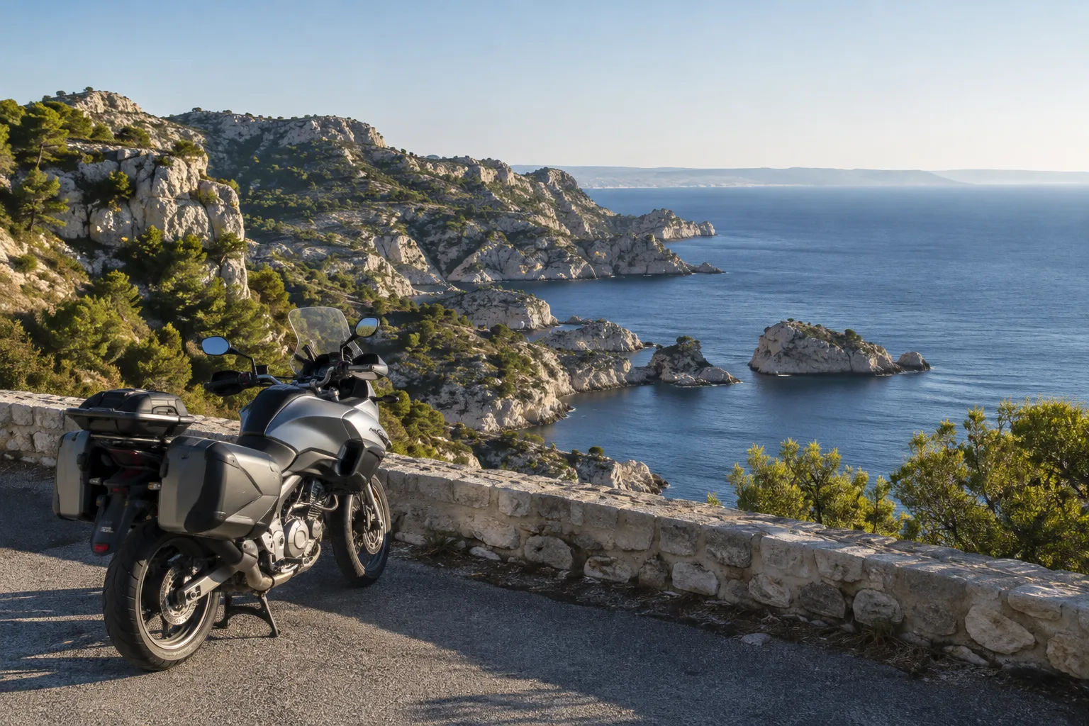 Une moto stationnée sur un belvédère de la Côte Bleue, au-dessus de la mer et des roches calcaires.