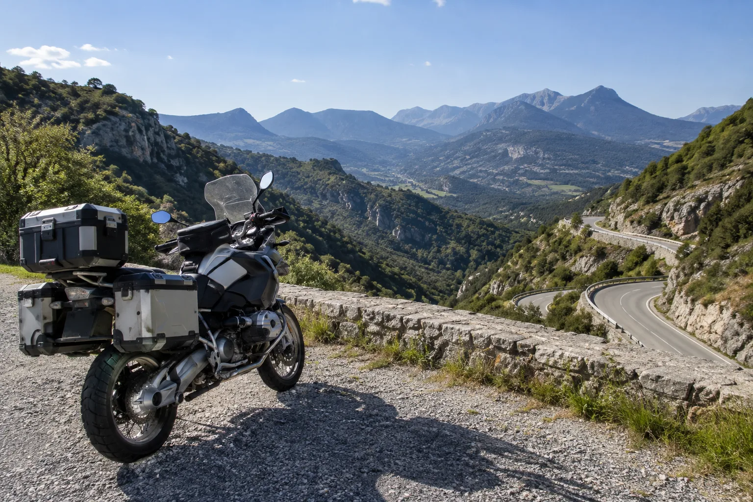 Une moto arrêtée sur un belvédère au-dessus d’une route sinueuse des Préalpes provençales.