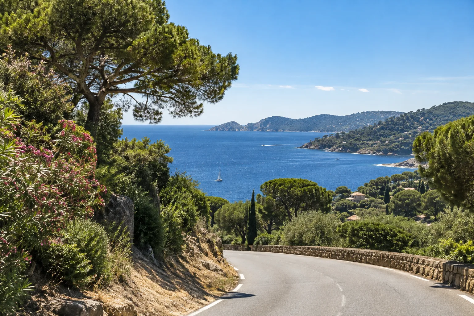 Une route côtière du sud de la presqu’île s’ouvre sur la mer entre des collines couvertes de végétation.